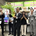 ２選を果たし、花束を掲げる新井氏